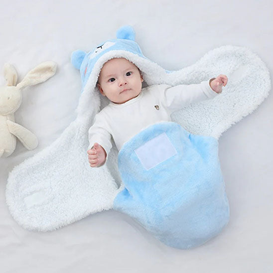 bebe allonge dans nid d'ange ourson bleu ouvert bras leve